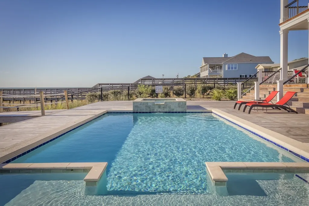 Concrete pool deck around a rectangular pool with a raised spa and a tile waterline