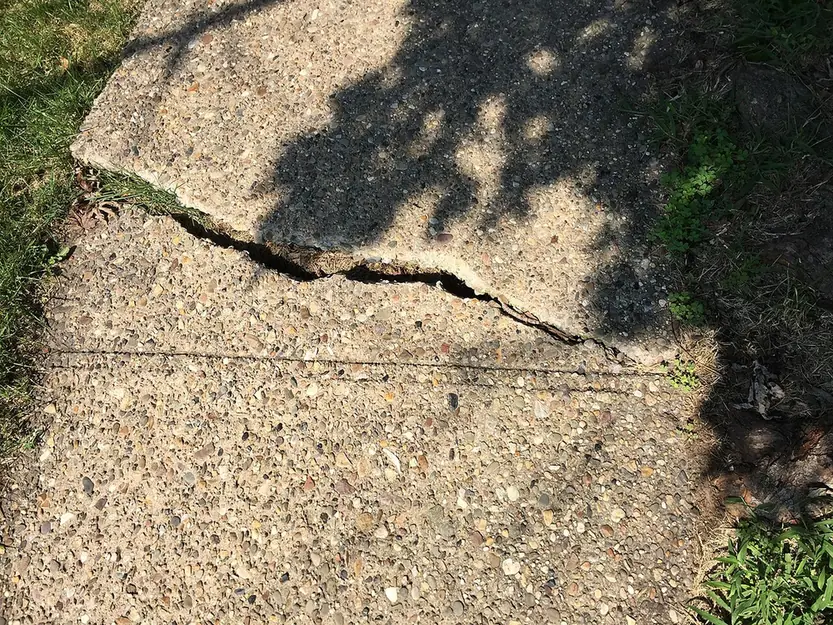 Cracked concrete slab with one side raised, the kind of damage older Bradenton FL pool decks show before resurfacing