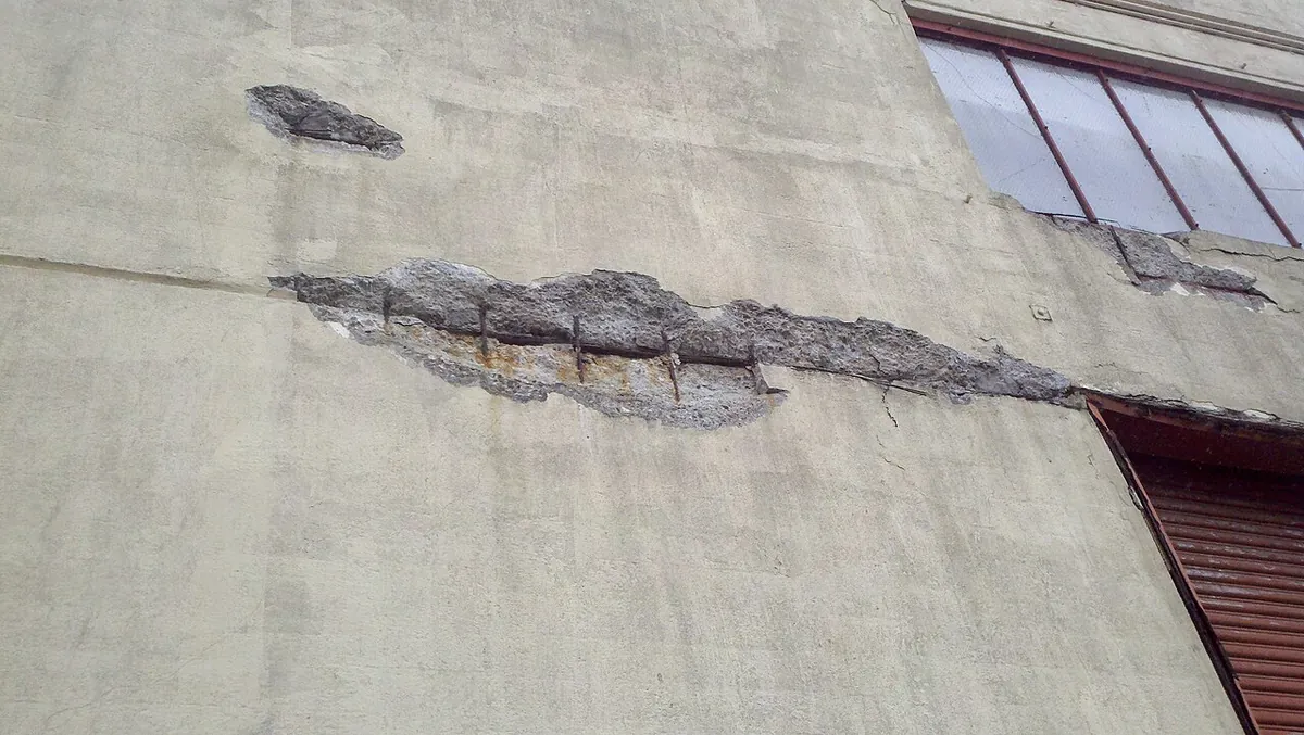 Spalled concrete broken away over rusting steel reinforcement