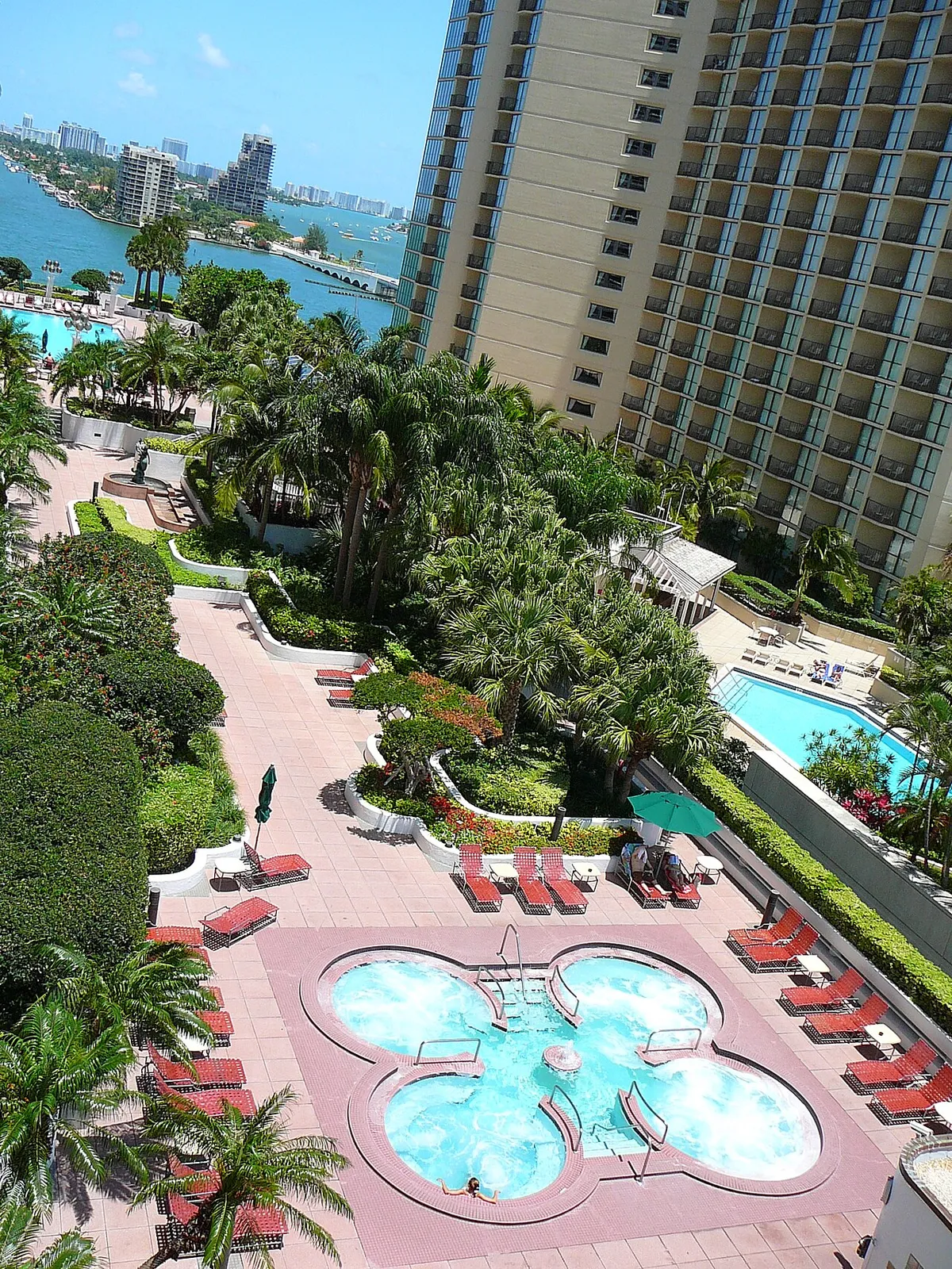 Large paver pool deck around a spa pool, seen from above, with planters and lounge chairs