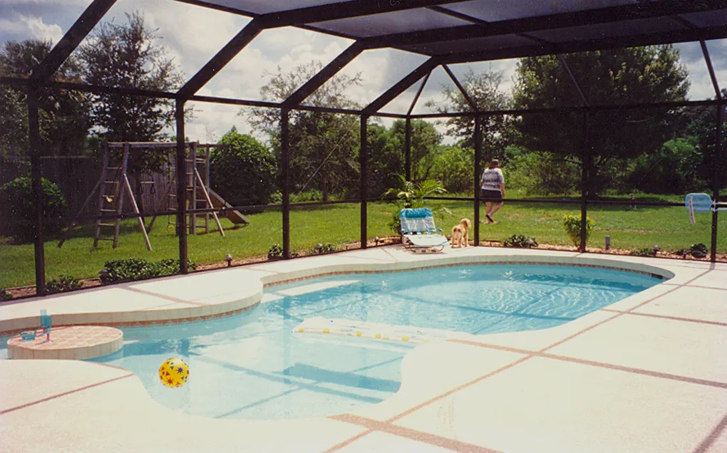 Rounded bullnose coping around a curved pool inside a Sarasota screened enclosure