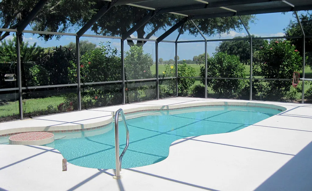 Pool deck resurfacing Lakewood Ranch FL area: a light textured deck inside a screened pool enclosure in Sarasota County