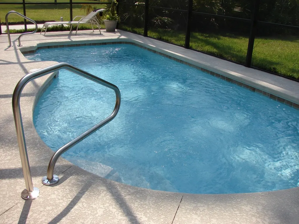 Light knockdown-textured cool deck around a pool inside a screened enclosure