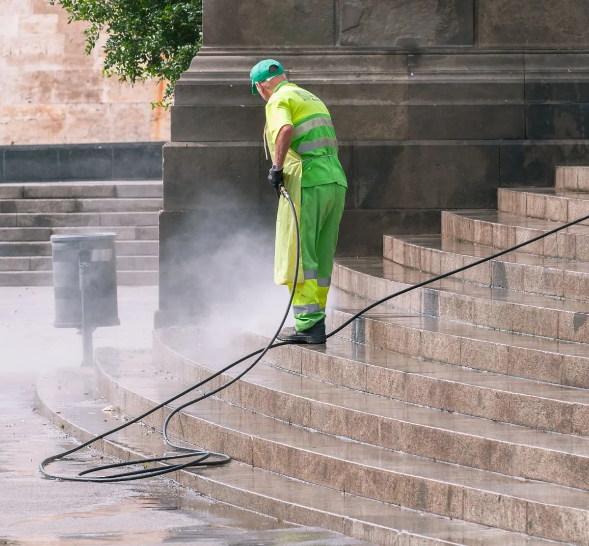 A worker pressure washing stone steps, the first step before painting a pool deck