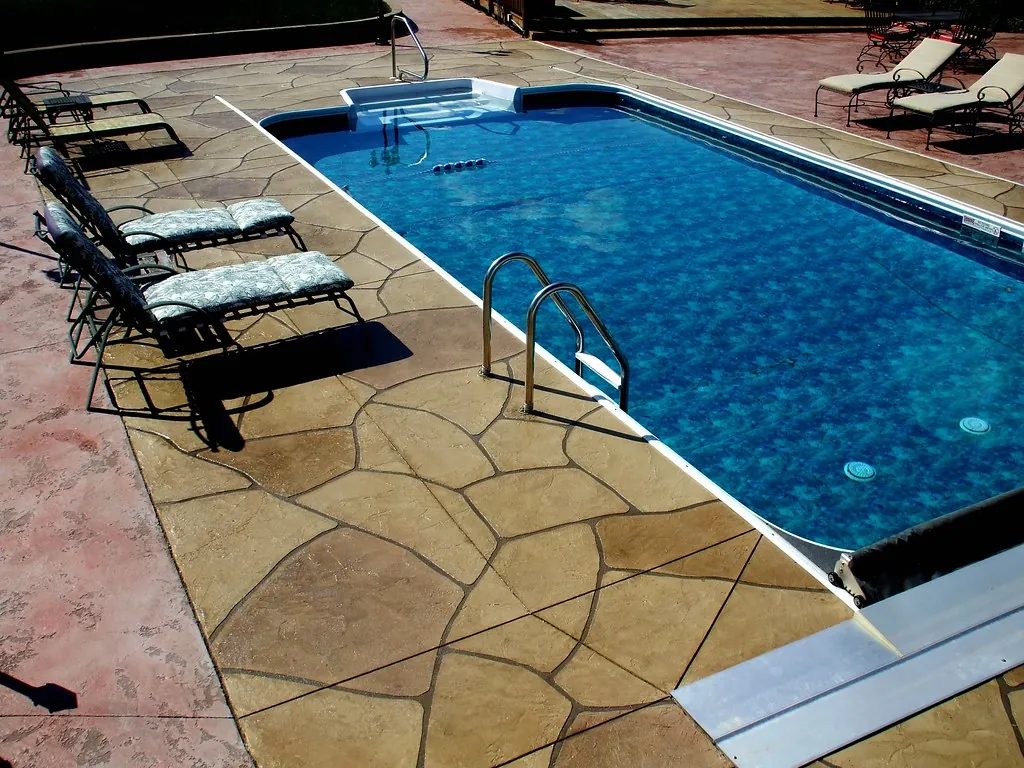 Stamped concrete pool deck with a stone pattern around a backyard pool