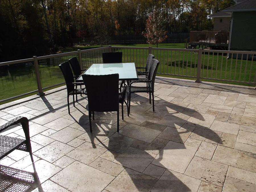 Ivory travertine paver deck with patio furniture and a glass railing